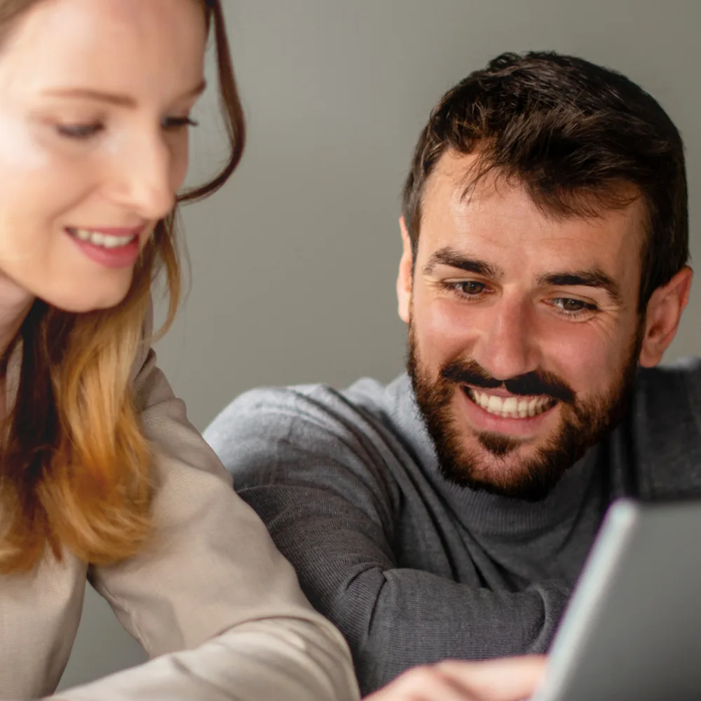 Une consultante et un consultant SODIGIX souriants travaillent ensemble devant un ordinateur portable